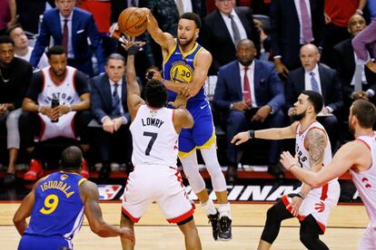 El jugador de Golden State Warriors Stephen Curry pasa el balón ante la oposición del jugador de Toronto Raptors Kyle Lowry.