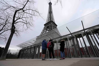 Turistas ven de lejos la torre Eiffel cerrada.