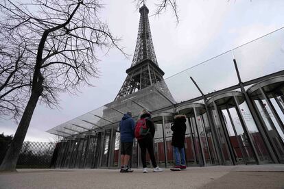 Turistas ven de lejos la torre Eiffel cerrada.