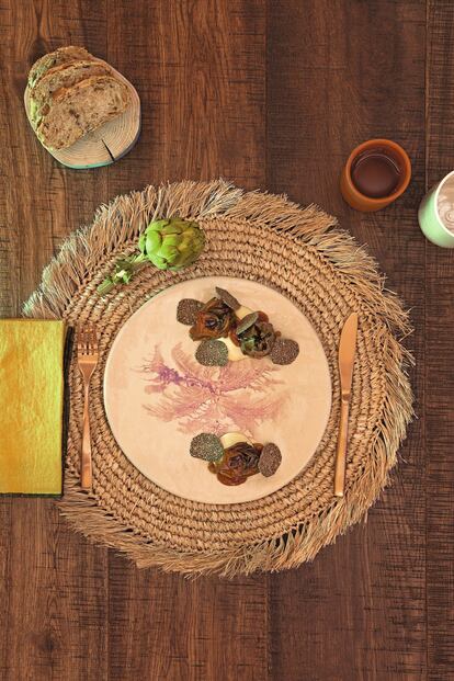 <p><b>ALCAHOFAS CON TRUFA Y CREMOSO DE RAÍCES</b></p> <p><b>Ingredientes. </b>Para cuatro personas: Para las alcachofas: 500 gramos de algas (kombu o lechuga de mar, por ejemplo), 5 litros de agua, 15 alcachofas. Para el aceite de guindilla: 1 guindilla, 100 gramos de aceite de oliva. Para el jugo: 1 kilo de garbanzos puestos en remojo ocho horas en agua tibia y sal, 1 kilo de zanahorias, 1 kilo de cebollas, 15 gramos de tamari o soja sin gluten. Para el puré de patata: 200 gramos de patata ratte, 20 gramos de leche vegetal, aceite de oliva virgen extra, 5 gramos de sal. Para la terminación: 1 trufa negra.</p> <p> <b>Elaboración. </b> Las alcachofas: 1. Infusionar las algas con agua durante 15 minutos a fuego vivo. Una vez hervidas, colar y reservar. 2. Limpiar las alcachofas cuidadosamente aprovechando parte del tallo. Introducirlas en el agua de cocer las algas. Cuando vuelva a arrancar el hervor, retirarlas del fuego y dejar que se enfríen en la misma agua. El aceite picante: 3. Verter el aceite en una sartén. Cuando esté caliente, agregar la guindilla picada sin las pepitas. 4. Dorar el chile y retirar del fuego. Dejar en la sartén hasta que enfríe y después colar. El jugo vegetal: 5. Poner todos los ingredientes a hervir a fuego lento durante 6 horas. 6. Colar, añadir el tamari y reducir hasta obtener una textura densa. El puré de patata: 7. Envolver las patatas en papel de aluminio y cocinar en el horno a 210 grados durante 20 minutos. 8. Cuando aún esté caliente la patata, pasarla por el pasapuré y después por un tamiz fino. 9. Poner la patata tamizada en un cazo junto a la leche y la sal. Batirla para mezclarla e incorporar el calor (es mejor en una plancha que sobre el fuego directo). 10. Añadir el aceite de oliva virgen extra. Rectificaremos de sal si es necesario. Antes de servir el plato: 11. Freír las alcachofas a 180 grados. Cuando estén doradas, sacar y escurrir el aceite sobrante con un papel de cocina absorbente. Presentación: 12. Poner en el plato una base de puré de patata. Sobre él, las alcachofas fritas, unas gotas del aceite picante y terminar glaseando con dos cucharadas soperas de jugo de vegetales. En el momento de servir el plato, con ayuda de un laminador de trufa, disponer unas láminas (seis por ración) directamente encima de la alcachofa.</p> <p>El mantel individual de rafia natural es de Mahe Homeware (60 euros, 6 unidades). La tabla que sirve de panera, de Con Alma Design, ha sido fabricada con madera de olivos caídos o podados (15 euros). El plato de gres es de la ceramista María Gómez de Agüero (25 euros). Los vasos de gres blanco de Laon Pottery tienen un acabado en esmalte fabricado por JooHyun Baek, ceramista de la firma (25 euros la unidad). Los vasos de cerámica sin esmaltar son de Alfarería Padilla, en Bailén.</p>