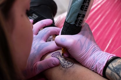 Una tatuadora traza una imagen de la Copa del Mundo en la pierna de un cliente, en el Coven Tatoo Studio en Olivos, Buenos Aires, el 27 December 2022.