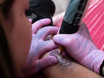 Una tatuadora traza una imagen de la Copa del Mundo en la pierna de un cliente, en el Coven Tatoo Studio en Olivos, Buenos Aires, el 27 December 2022.