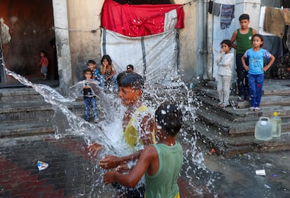 Children displaced at a school in Khan Younis, in the southern Gaza Strip, throw water on themselves to cool down, July 1, 2026.