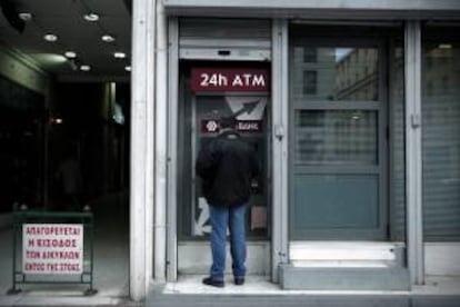 Un hombre saca dinero de un cajero automático en una sucursal del Banco Popular de Chipre en Atenas (Grecia) hoy.