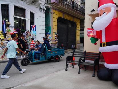 Un grupo de personas pasa por una calle con decoraciones navideñas en La Habana.
