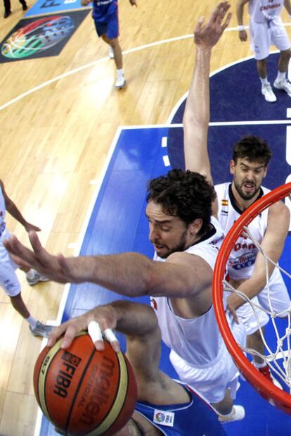 Pau Gasol bloquea a un adversario mientras Marc permanece a la expectativa.