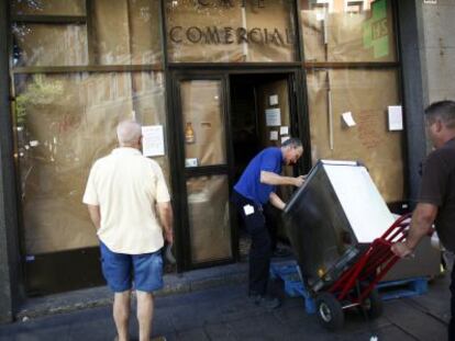 Dos empleados transportan un mueble durante el cierre del Café Comercial.
