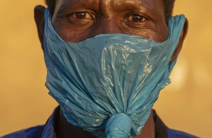 Un hombre usa una bolsa de plástico en la cara como mascarilla facial contra la propagación del coronavirus, en Johannesburgo, Sudáfrica.