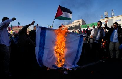 Manifestantes iraníes queman una representación de la bandera israelí mientras uno de ellos ondea una bandera palestina en una concentración celebrada en Teherán el sábado 18 de noviembre de 2023.