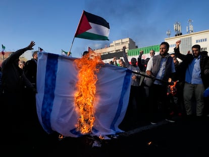 Manifestantes iraníes queman una representación de la bandera israelí mientras uno de ellos ondea una bandera palestina en una concentración celebrada en Teherán el sábado 18 de noviembre de 2023.