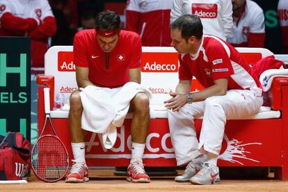 Federer, cabizbajo, escucha los consejos de Severin Luthi, el seleccionador suizo
