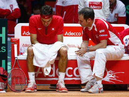 Federer, cabizbajo, escucha los consejos de Severin Luthi, el seleccionador suizo