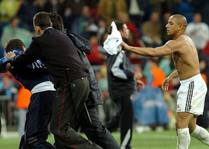 El jugador del Real Madrid Roberto Carlos acude a regalarle la camiseta al aficionado que saltó a campo a pedírsela.