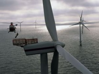 Un técnico desciende de un helicóptero para realizar labores de matenimiento en un molino marino.