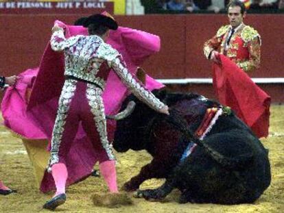 Un peón intenta levantar al quinto toro, invlálido como toda la corrida, tirándole del rabo.