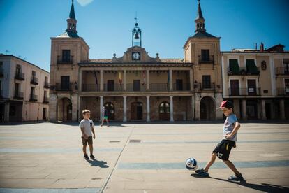 Dos niños juegan al fútbol en la plaza del Burgo de Osma, en Soria.