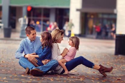 Una familia disfruta en el suelo de una v&iacute;a p&uacute;blica. 