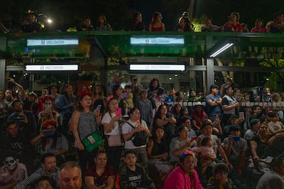 Cientos de personas congregadas en una estación de Metrobús ven el paso de las Catrinas, sobre Paseo de la Reforma.