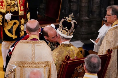 El príncipe de Gales besa a Carlos III tras ser coronado. Instantes antes, el príncipe Guillermo se ha arrodillado antes su padre para jurarle lealtad y fidelidad en el histórico juramento de sangre durante la coronación.