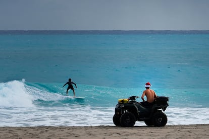 Un salvavidas con un gorro de Pap Noel observa a un surfista en la vspera de navidad, en Palm Beach, Florida.  