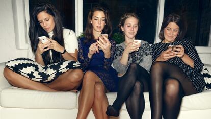 Un grupo de mujeres mira sus teléfonos móviles.