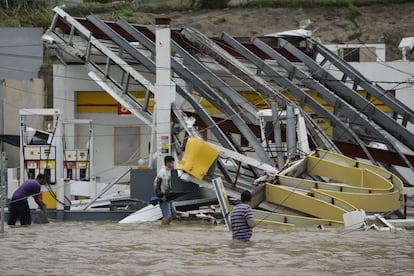 Varias personas pasan delante de una gasolinera inundada y destrozada por el impacto del huracán María en Humacao, Puerto Rico. El huracán ha sido el más fuerte que ha tocado tierra en la isla de los últimos 80 años.