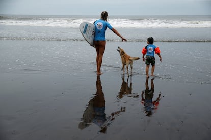 La instructora Nette Klement encamina al ni?o Lucas Rivera al mar para darle una leccin de surf.