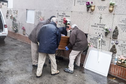 Una cuadrilla de sepultureros mete un féretro en un nicho. Era el de una mujer de 100 años a cuyo entierro nadie acudió.