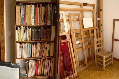 Una de sus estanterías de libros y bastidores para sus piezas.