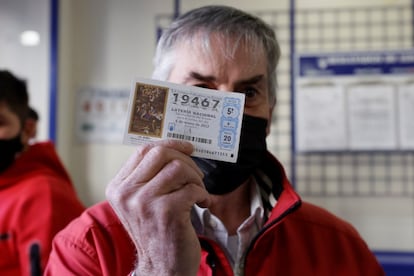 Un afortunado con el número 19467 celebra el tercer premio del sorteo de la Lotería del Niño en una administración en Valencia, este jueves.