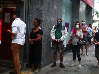 As pessoas esperam na fila para entrar em um banco durante o surto da doença por coronavírus, no bairro de Copacabana, no Rio de Janeiro.