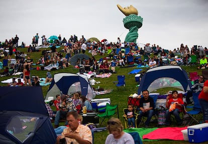 La antorcha de la Estatua de la Libertad se ve detrás de una multitud de personas que esperan el comienzo de los fuegos artificiales durante las celebraciones del 4 de Julio en el parque Gas Works, en Seatle.