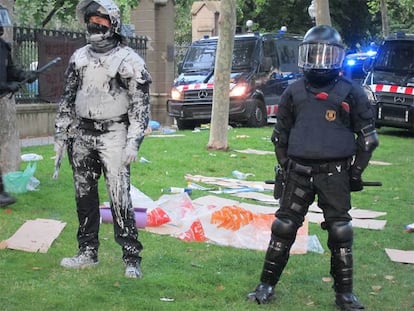 Algunos de los Mossos d'esquadra que forman el cordón policial ante los indignados del Parlament han quedado cubiertos de pintura arrojada por los manifestantes.