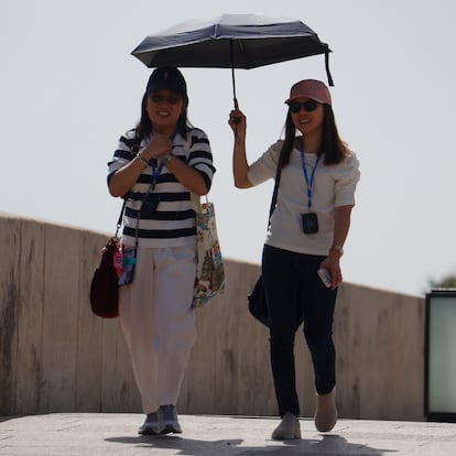 CÓRDOBA, 10/08/2025.- Dos personas se protegen del sol con un paraguas para aliviar las altas temperaturas este domingo en Córdoba. EFE/Salas