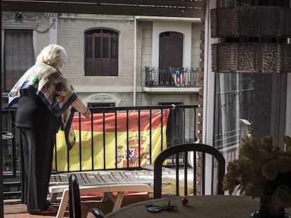 Una vecina coloca en su balc&oacute;n una bandera espa&ntilde;ola, frente a una casa con la estelada nacionalista catalana, en una calle de Barcelona.
 
 
 