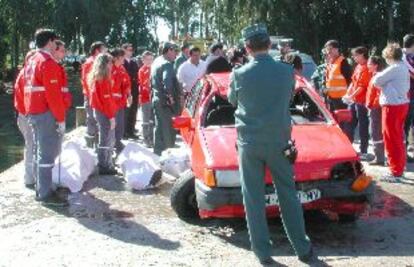 Guardias civiles y miembros de Cruz Roja observan el coche en el que viajaban los tres fallecidos.