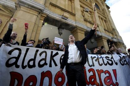 El nuevo alcalde donostiarra, Juan Carlos Izagirre (Bildu) blande la vara de mando ante un cartel que dice: "El cambio ha llegado a San Sebastián".