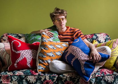 El diseñador Luke Edward Hall entre los cojines que ha diseñado esta primavera para The Rug Company. |