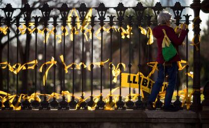 Una dona col·loca llaços grocs a la tanca del Parc de la Ciutadella.