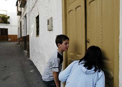 Dos niños miran por una rendija el interior de la casa donde aparecen las caras.