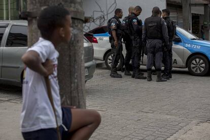 Uma criança observa um grupo de policiais na Cidade de Deus, no Rio.