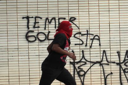 Manifestante corre durante protesto: ao fundo, parede do Ministério da Agricultura, pichado na manifestação. 