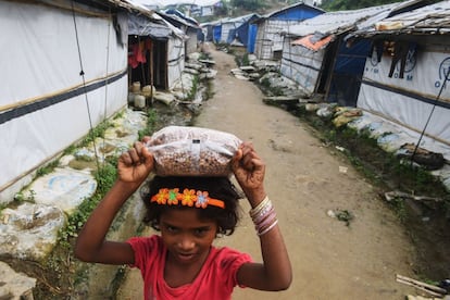 Una niña Rohingya refugiada carga una bolsa de grano en la cabeza en el campamento para refugiados de Unchiprang, en Teknaf, próximo a Cox's Bazar (Bangladesh), el 24 de agosto de 2018. La repatriación se evapora para un millón de refugiados Rohingyas con necesidades cada vez mayores, desde que hace un año estallará el conflicto en Myanmar.