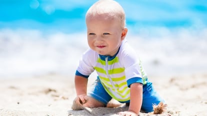 Bebé en la playa con un bañador de cremallera.