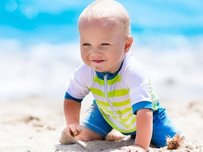 Bebé en la playa con un bañador de cremallera.