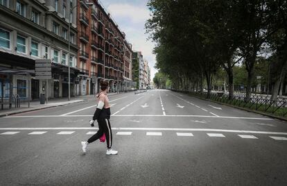Una mujer cruzando un vacío Paseo del Prado de Madrid, durante el estado de alarma.