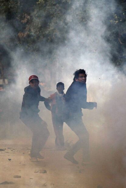 Tres manifestantes lanzan piedras a la policía durante los disturbios del viernes en Túnez.