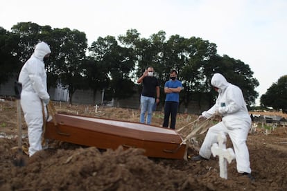 Los hermanos Carlos Alexandre y Wagner Cardninot asisten al funeral de su padre, de 76 años, muerto por coronavirus. La fotografía está tomada en el cementerio de São Francisco Xavier de Rio de Janeiro (Brasil). La Fiscalía brasileña dio un plazo de 72 horas para que el Ministerio de Salud explique la omisión de datos consolidados sobre la pandemia del coronavirus, decisión que fue adoptada desde el último viernes y desató un alud de críticas contra el Gobierno del presidente, Jair Bolsonaro.