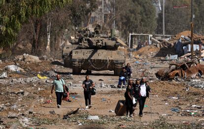 Un grupo de palestinos pasa junto a varios tanques mientras huye hacia el norte por una carretera en el distrito de Zeitoun, en las afueras del sur de Ciudad de Gaza, este viernes.