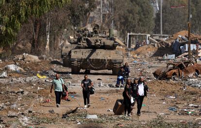 Un grupo de palestinos pasa junto a varios tanques mientras huye hacia el norte por una carretera en el distrito de Zeitoun, en las afueras del sur de Ciudad de Gaza, este viernes. 